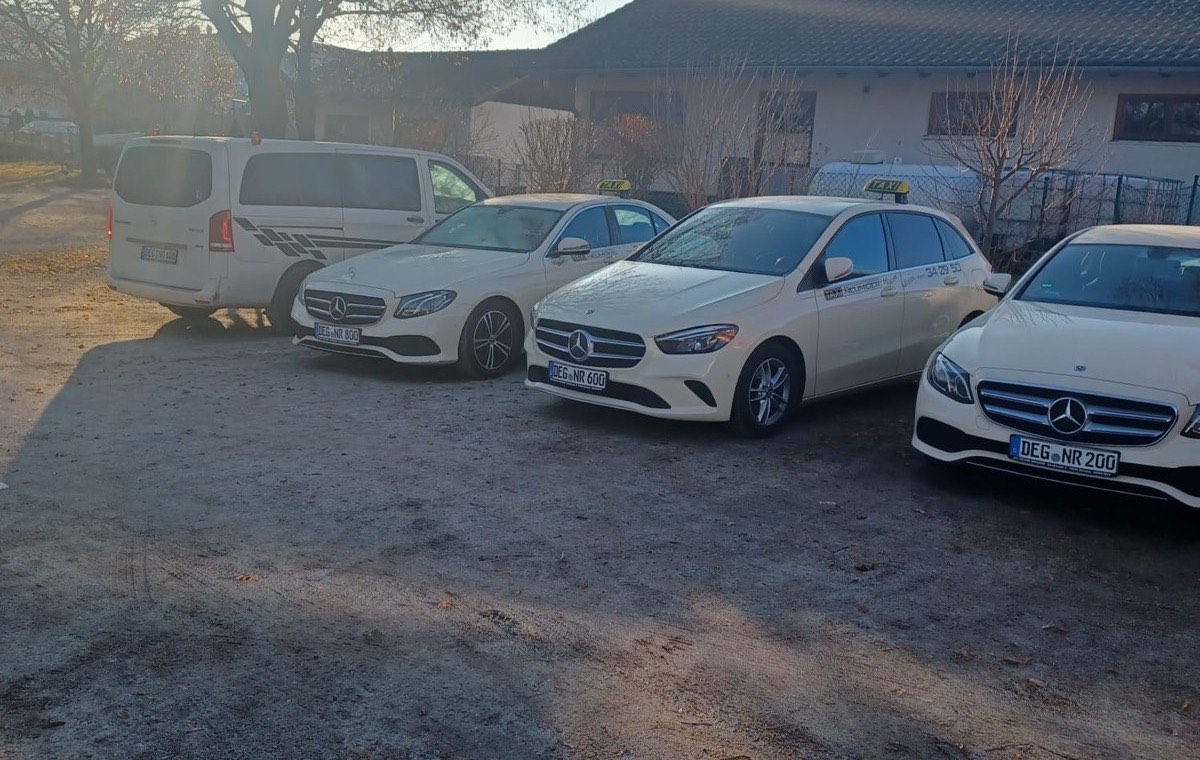 Der Fuhrpark von Taxi Neumeier: vier helle Mercedes-Taxis und ein Vito-Großraumwagen im Morgenlicht